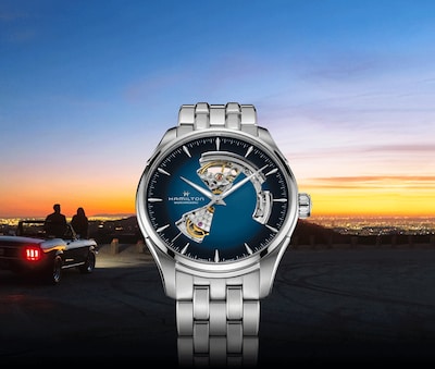 Hamilton watch with blue dial on sunset background with couple sitting on car. Tap to shop Hamilton watches image