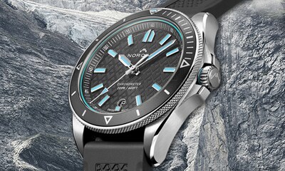 Norqain Adventure Collection. Image of grey and turquoise watch on icy stone background. Tap to Shop Adventure collection image