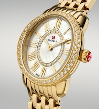 Close-up of a gold Michele watch with diamond-studded bezel, mother-of-pearl dial, Roman numerals, and a gold link bracelet. image